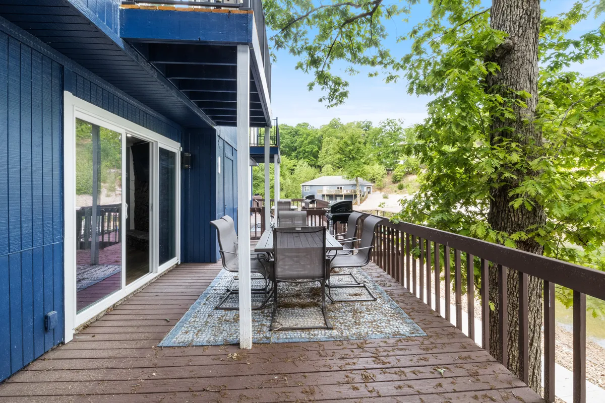 An inviting outdoor dining area with a table and comfortable chairs set on a deck overlooking scenic water views. The space is ideal for group meals, picnics, and gathering together after swimming or playing in the lake.