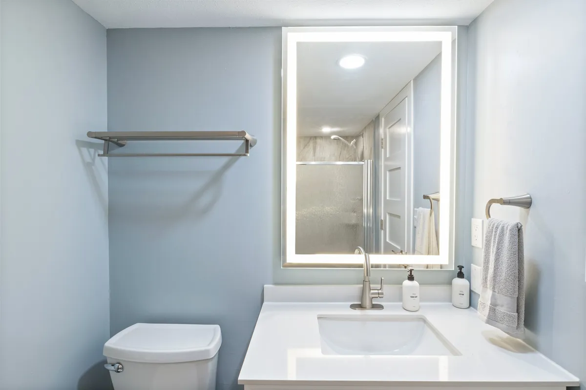 A modern bathroom with a mirrored, backlit vanity, sleek faucet, and neatly arranged towel rack. The design is clean and contemporary, inviting guests to refresh after a day of adventure or prepare for an evening out.