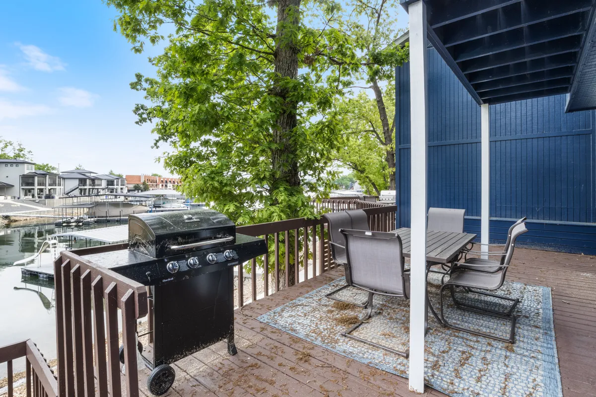 The image showcases an inviting outdoor dining area overlooking a tranquil marina at sunset, featuring a grill, spacious dining table, and a beautiful water view. The setup evokes a sense of relaxation and togetherness, perfect for gathering with friends and family to enjoy alfresco meals by the lake.