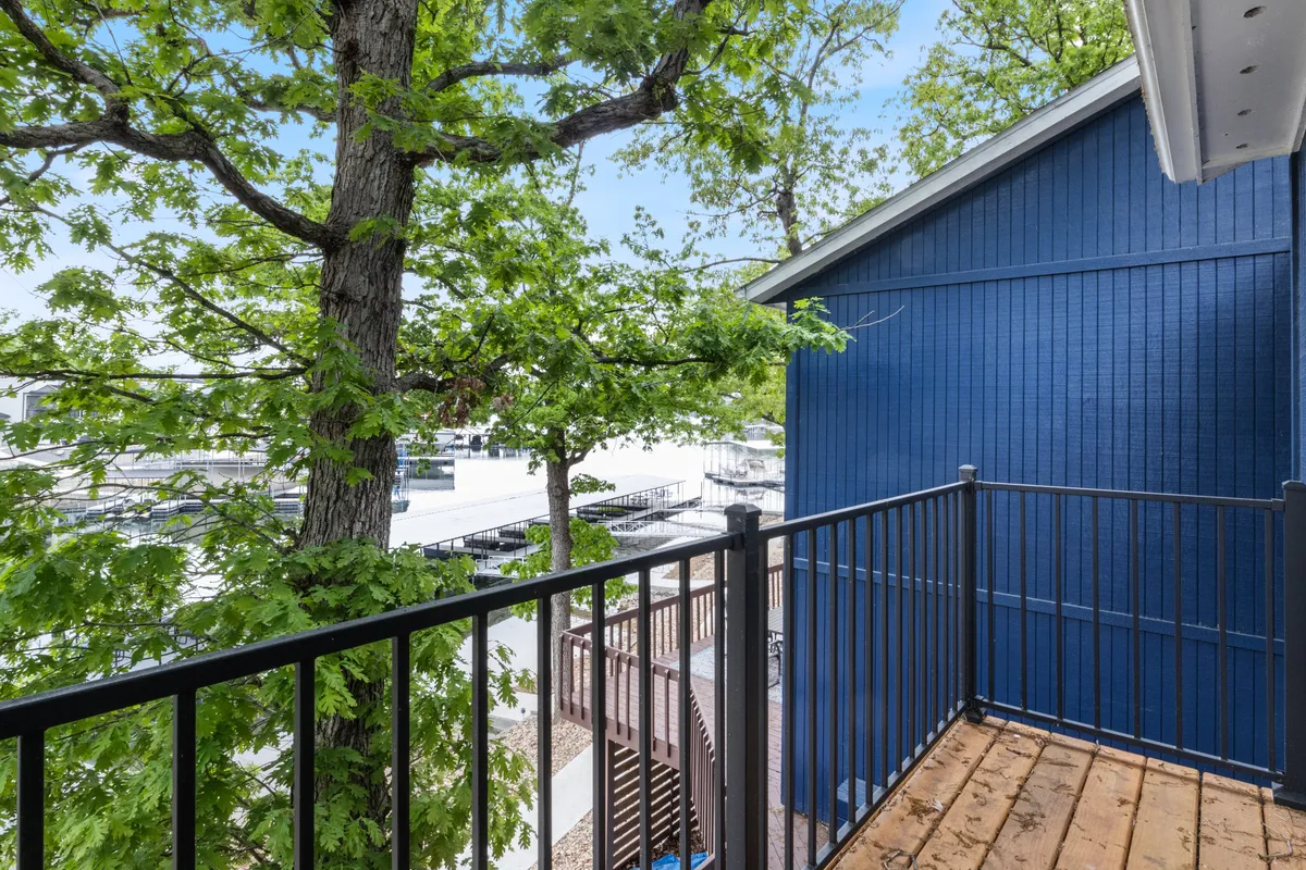 This exterior image captures a serene scene with lush green trees partially framing a blue building with balcony railings, evoking the feeling of being surrounded by natural beauty, relaxation spaces, and opportunities for social connection outdoors.
